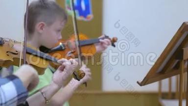 在<strong>音乐学校</strong>的<strong>音乐</strong>课上，小男孩学生和老师一起拉小提琴。